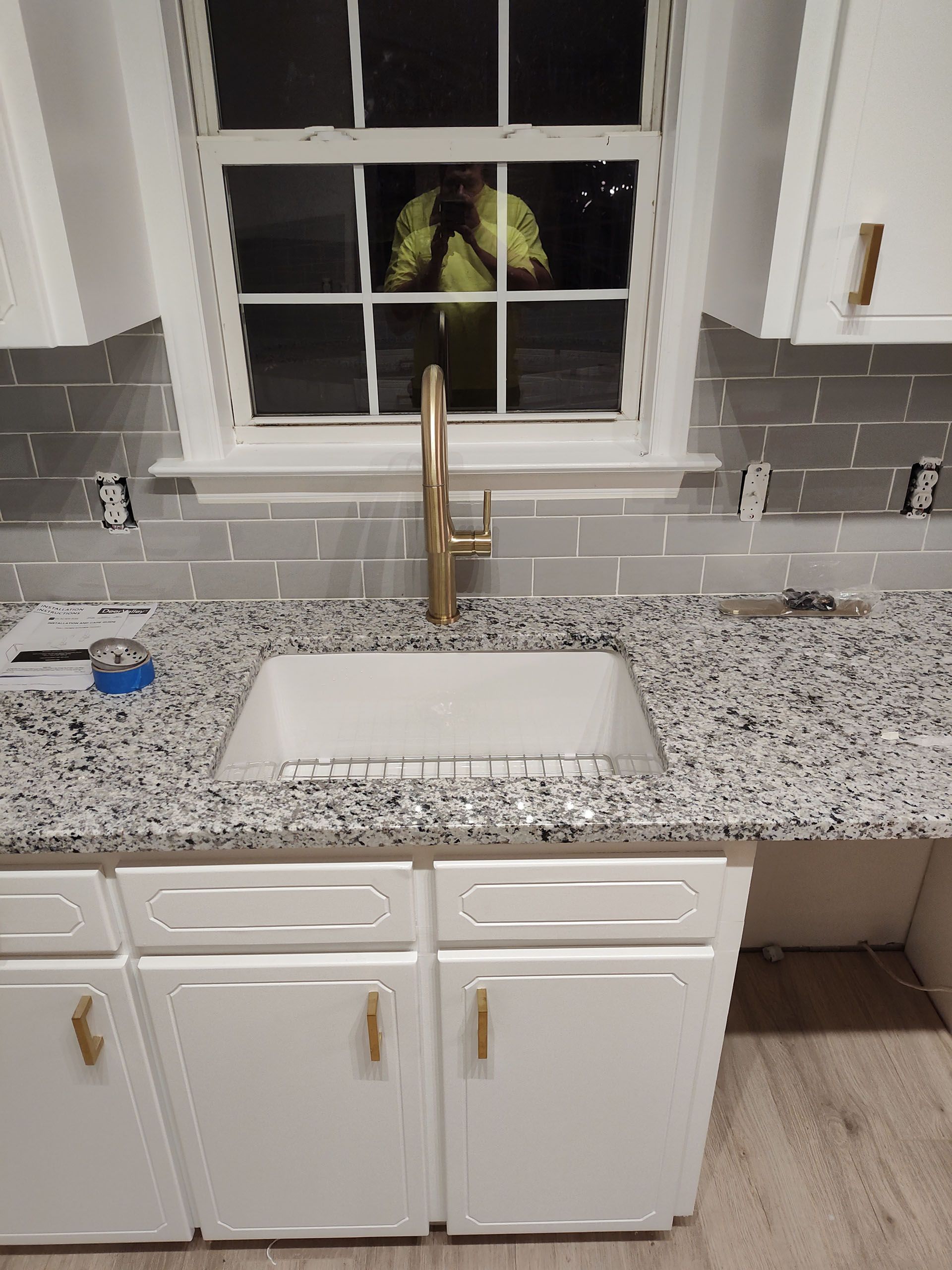 A kitchen with a sink , cabinets , and a window.