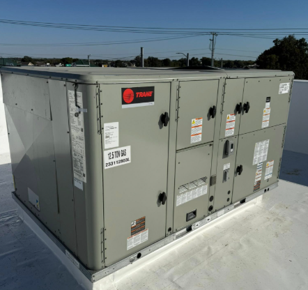 Gray rooftop HVAC unit with Trane logo, on a white roof, clear sky.