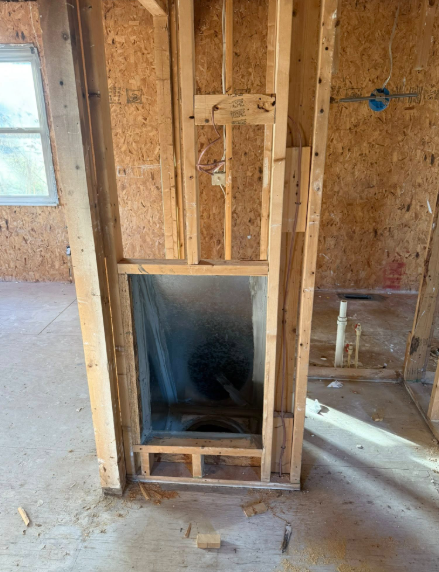 Interior framing with a metal box, likely for a fireplace, against OSB wall. Electrical wiring is visible.
