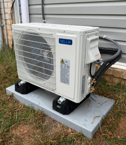 White Delta air conditioning unit on a gray base in a yard.