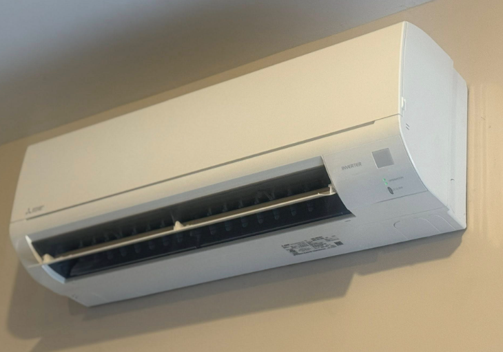 White wall-mounted air conditioning unit on a beige wall.
