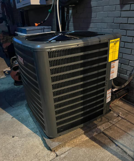 Gray air conditioning unit outside on concrete.