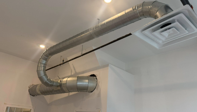 Metal ductwork snaking across a white ceiling with vents.