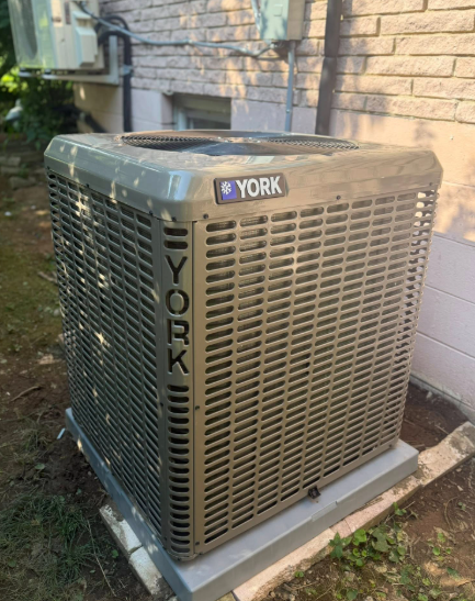 Gray York air conditioning unit next to a brick wall.