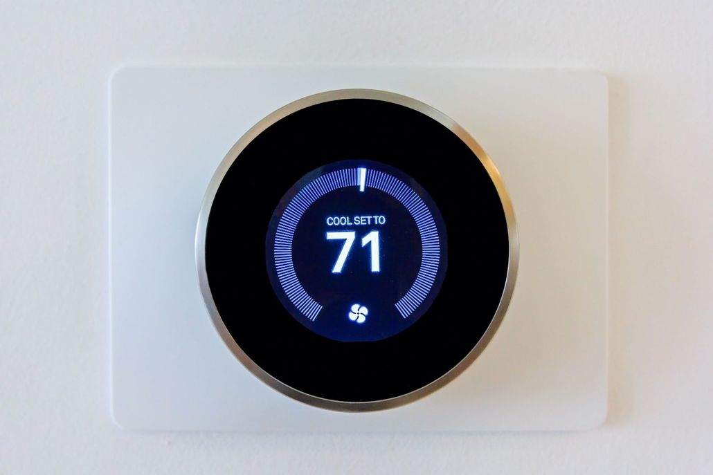 Digital thermostat displaying 71 degrees. White square mount with a black and silver round dial.
