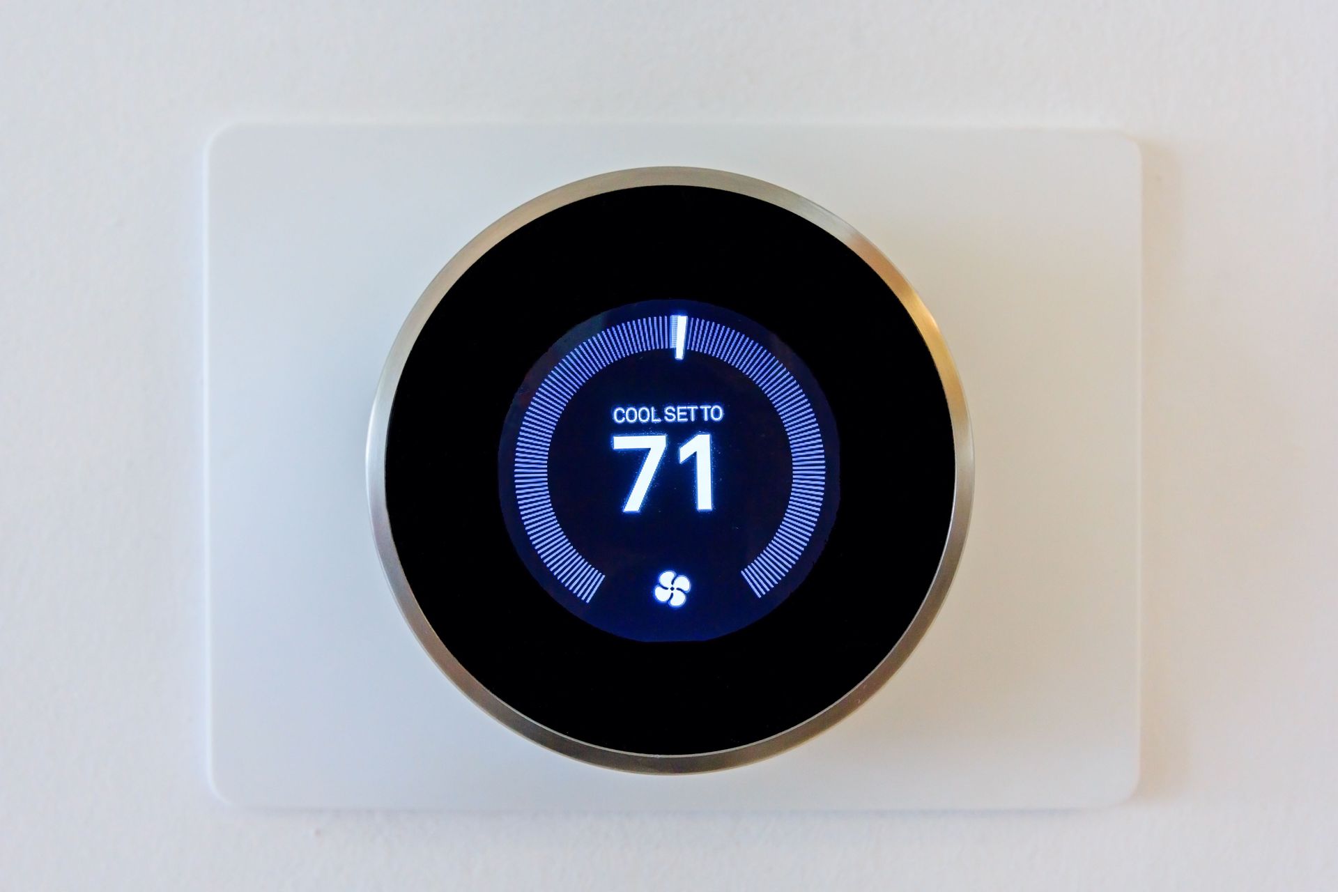 Digital thermostat displaying 71 degrees. White square mount with a black and silver round dial.