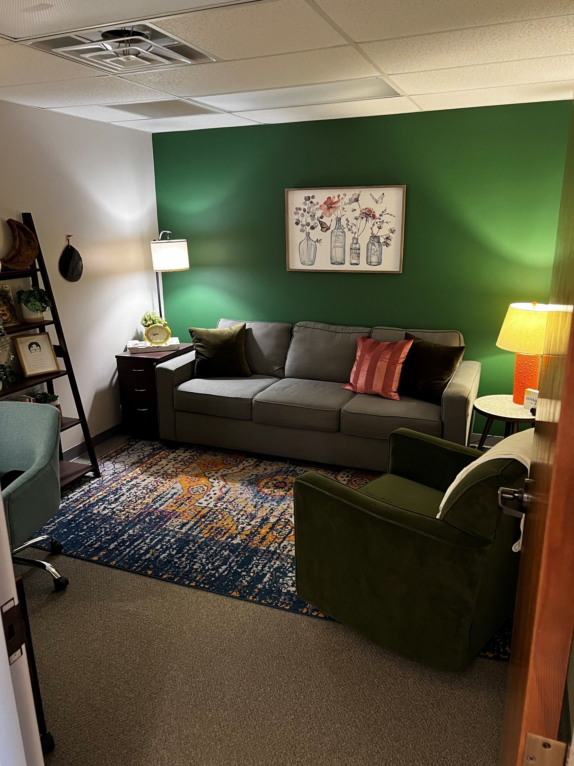 A living room with a couch , chair , rug and green walls.
