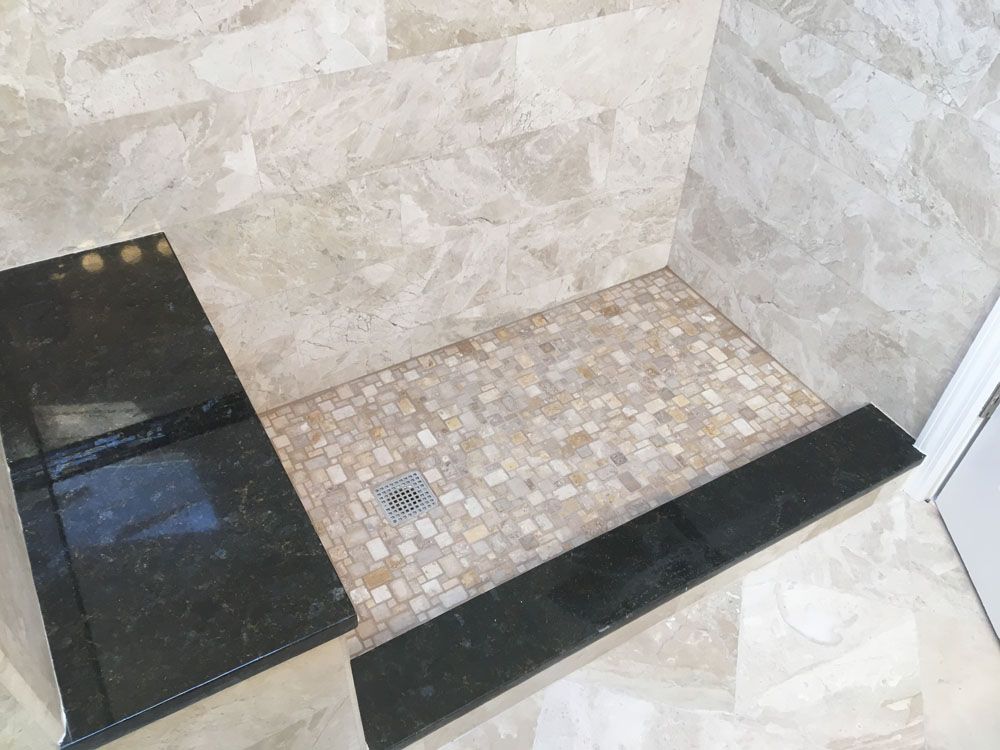 a bathroom with a walk-in shower and a black countertop
