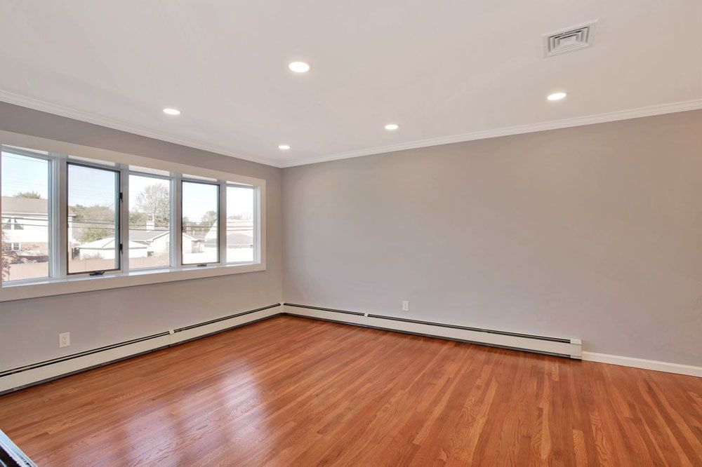 an empty living room with hardwood floors and lots of windows