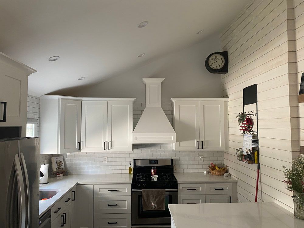 a kitchen with cabinets, a stove, a refrigerator, and a clock