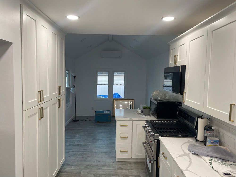 a kitchen with white cabinets, a stove, and a microwave