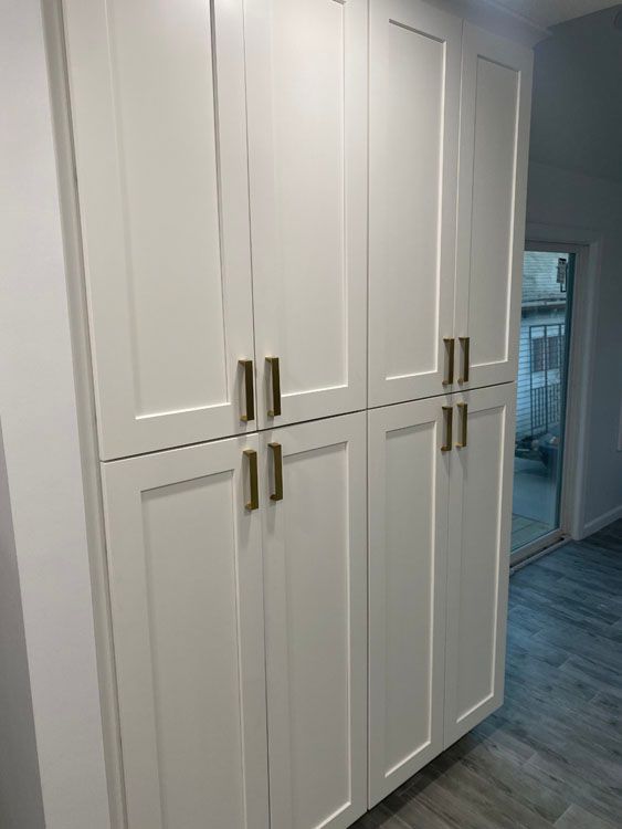 a row of white cabinets with gold handles 