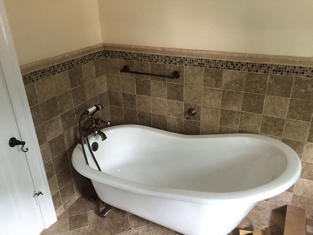 a bathtub is sitting in a bathroom next to a tiled wall
