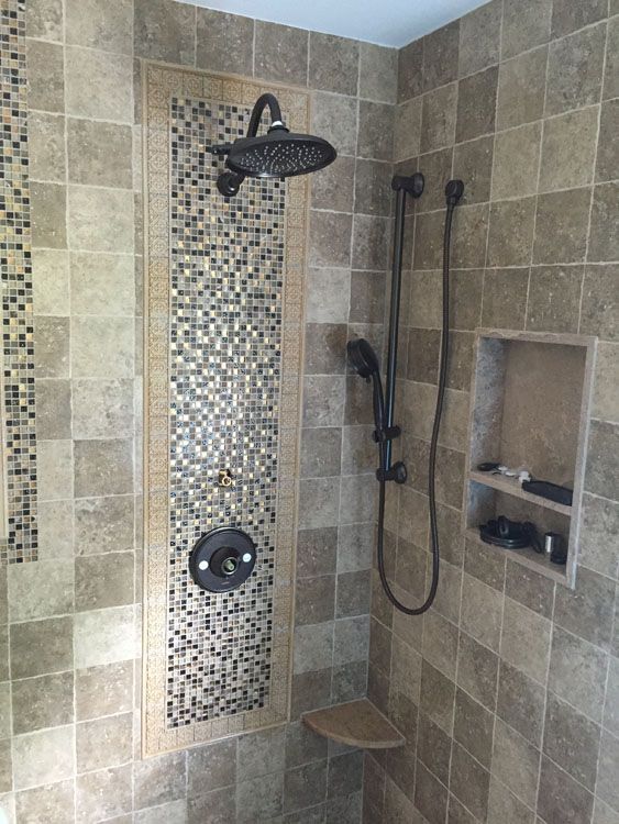 a shower with a tiled wall and a shower head