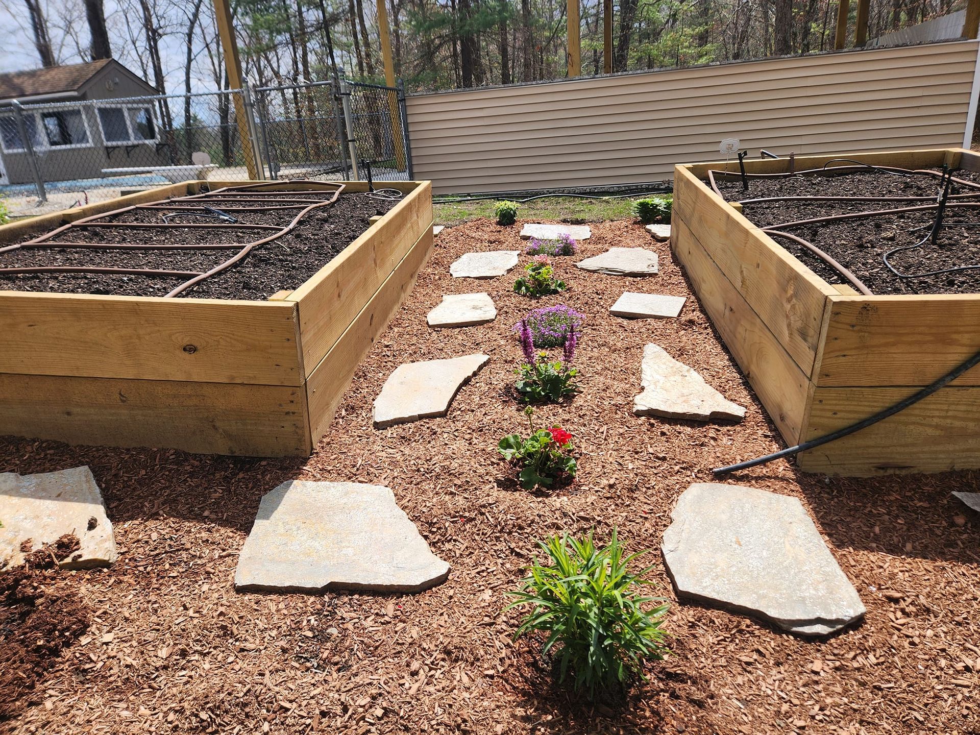 a wooden garden bed with flowers and rocks in it