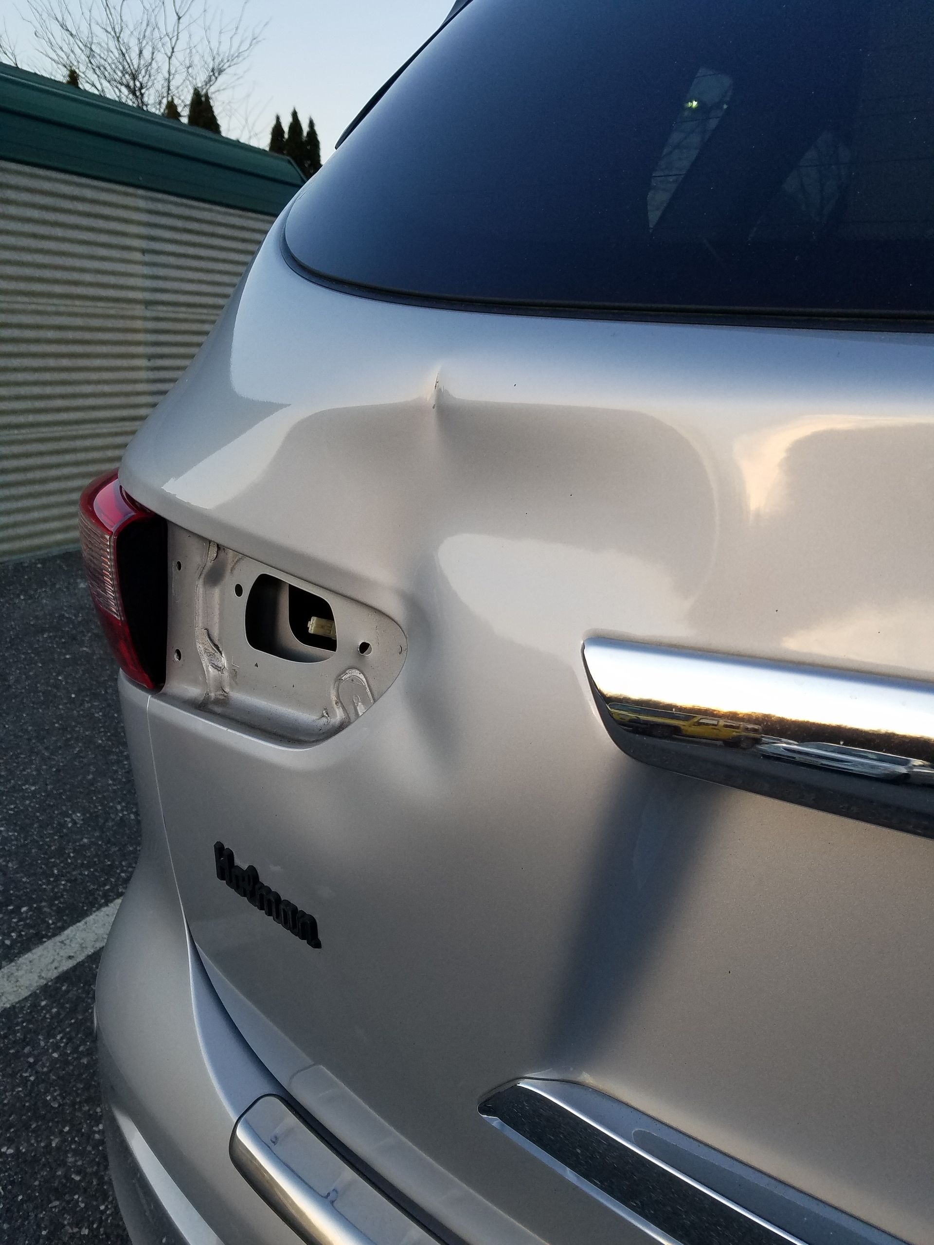 Damaged silver SUV rear with a dented hatch and missing taillight assembly