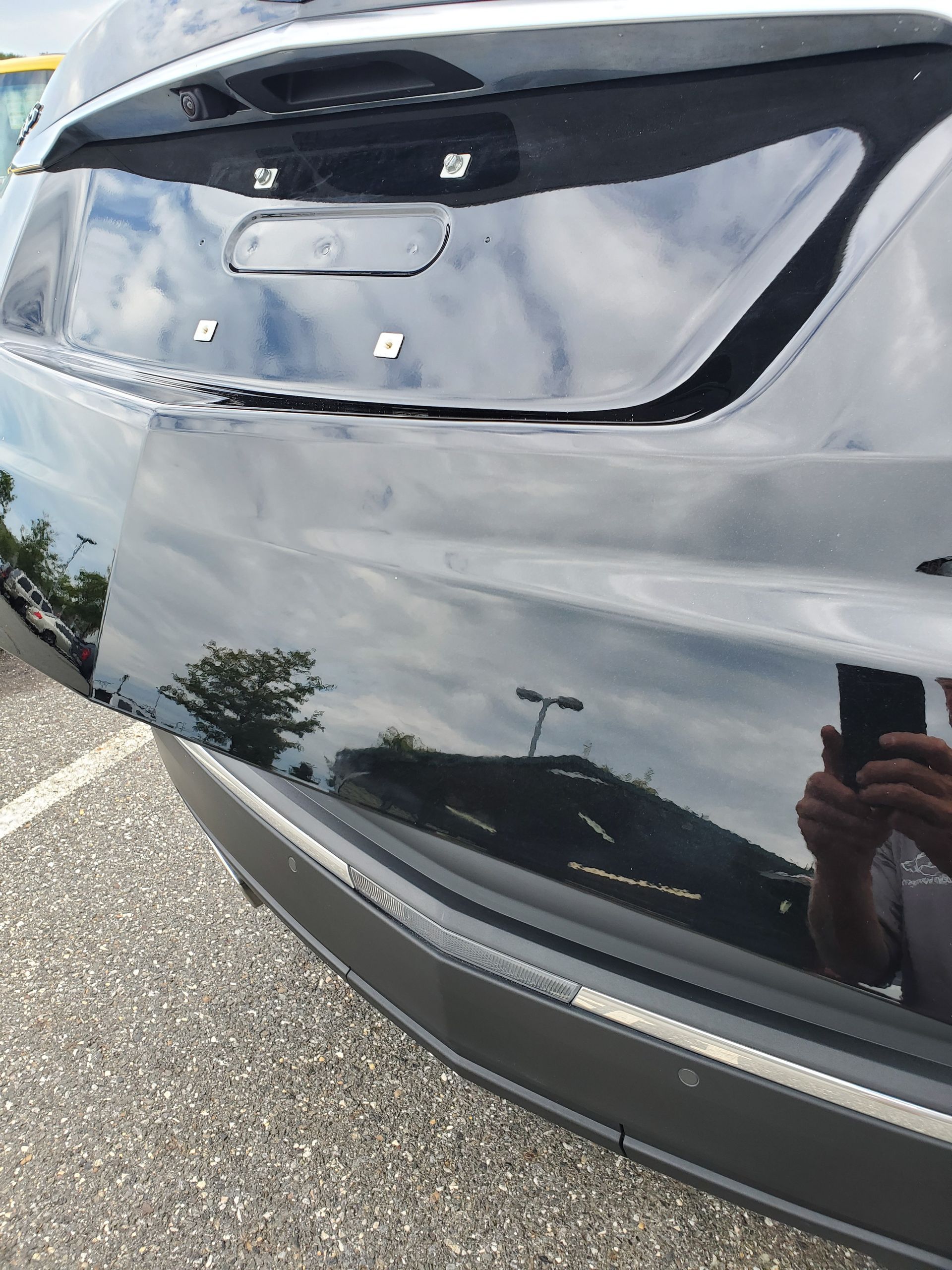 Close-up of a black car’s rear hatch and bumper in a parking lot, with a license plate area centered above.