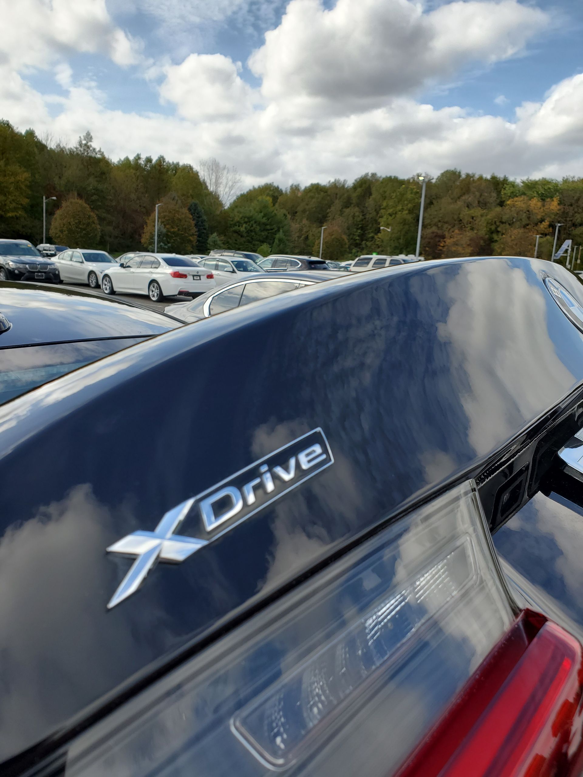 Close-up of a blue XDrive car badge on a vehicle in a parking lot