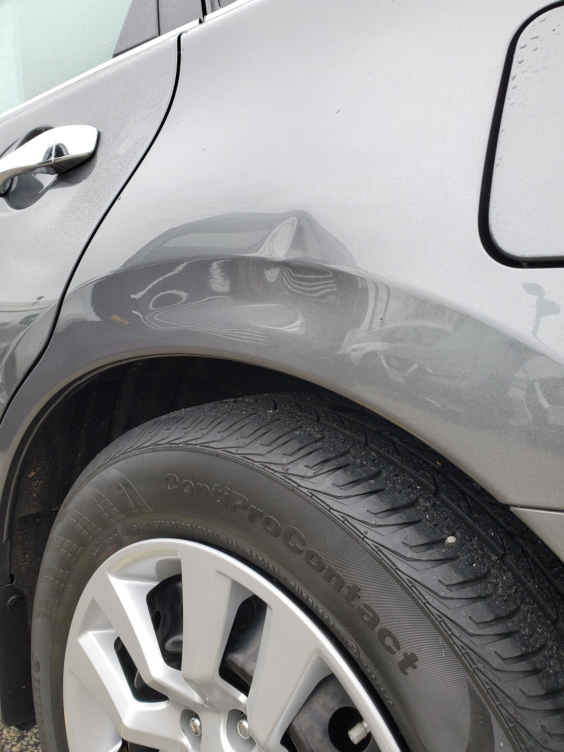 Silver car with a dented rear fender above the wheel
