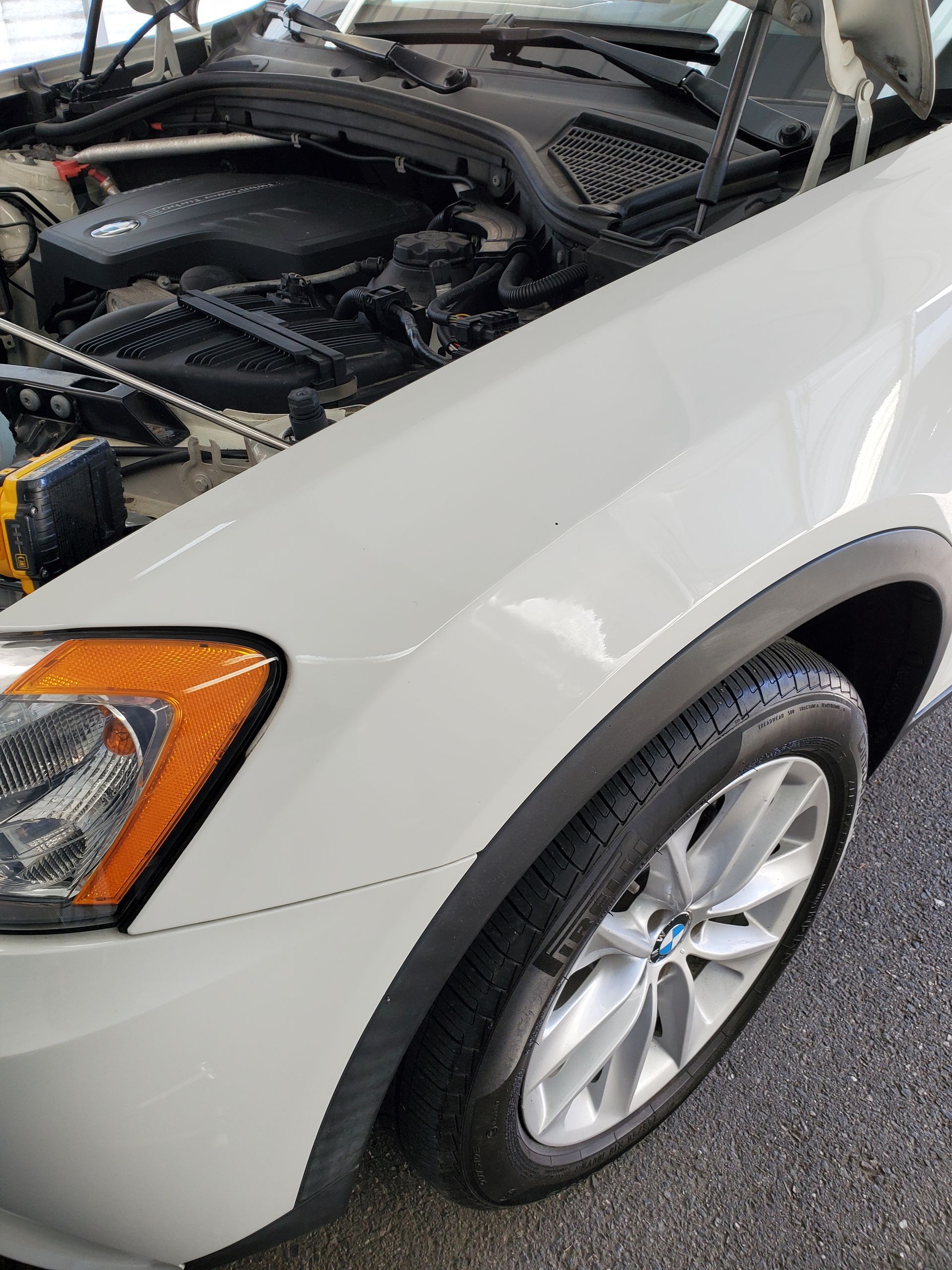 White car with hood open, showing the front left side and engine compartment