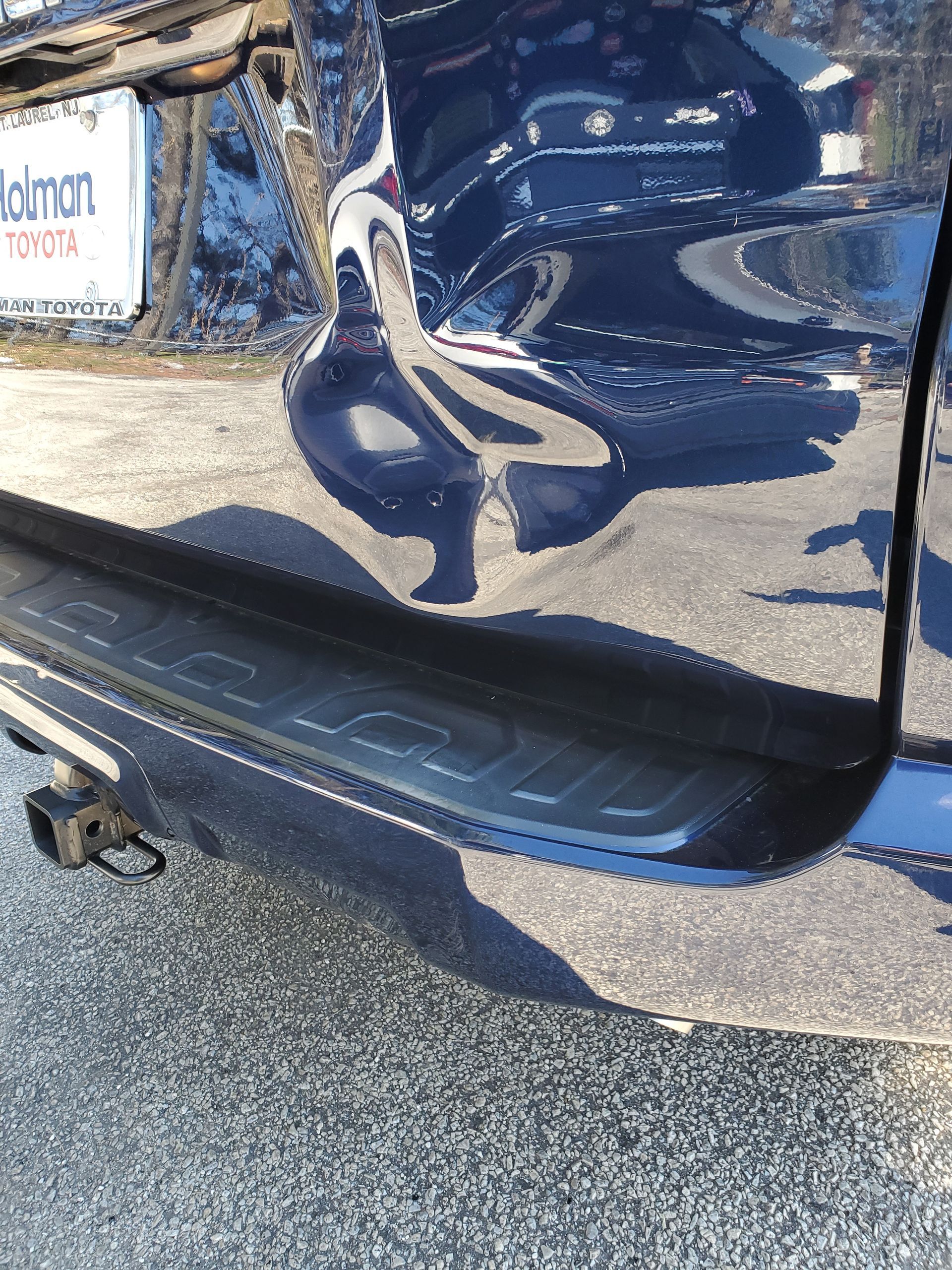 Damaged dark blue car door and rocker panel with a large dent and scraped paint
