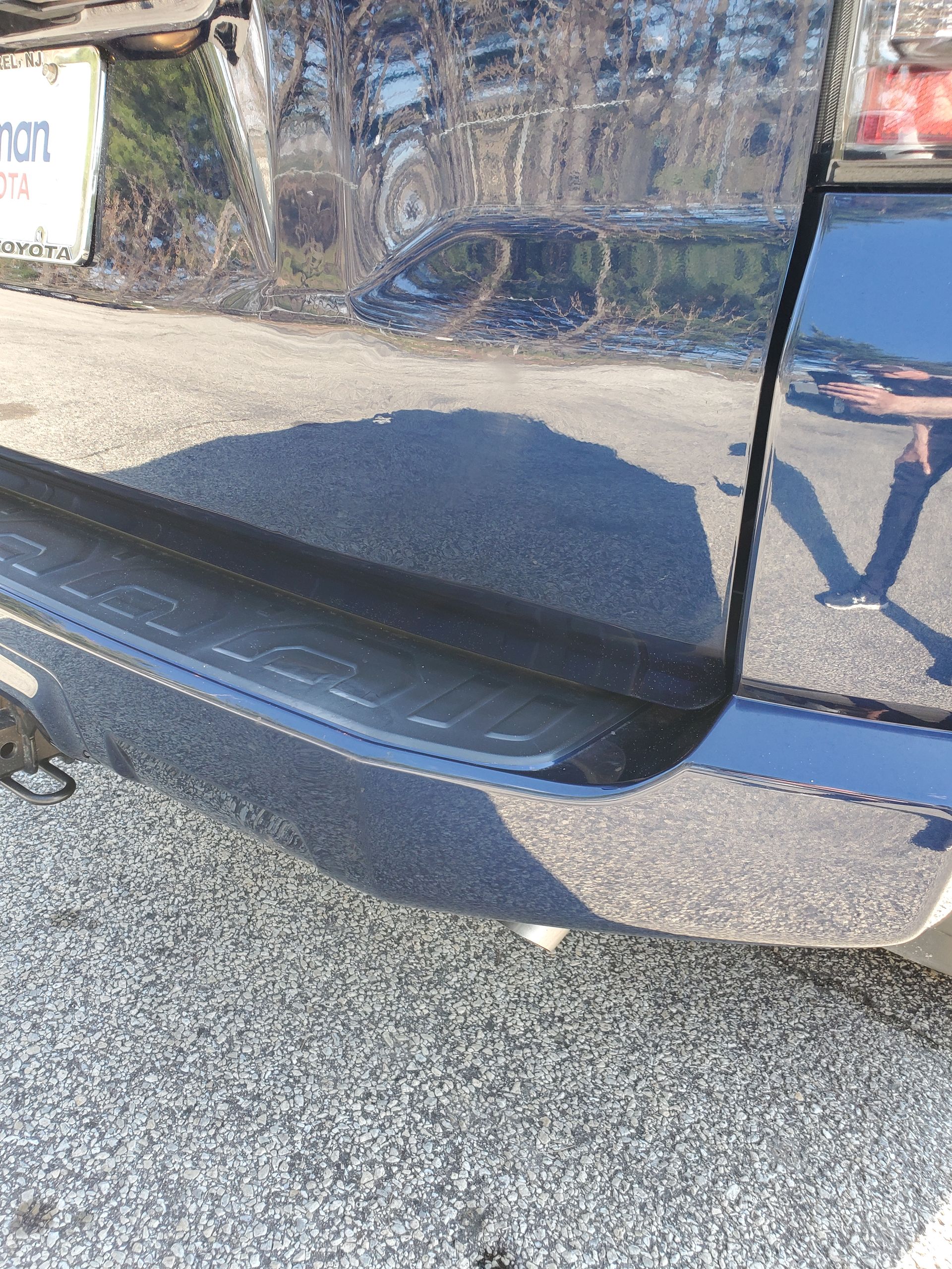 Close-up of a blue car’s rear bumper and side panel with visible scuffs and paint scratches.
