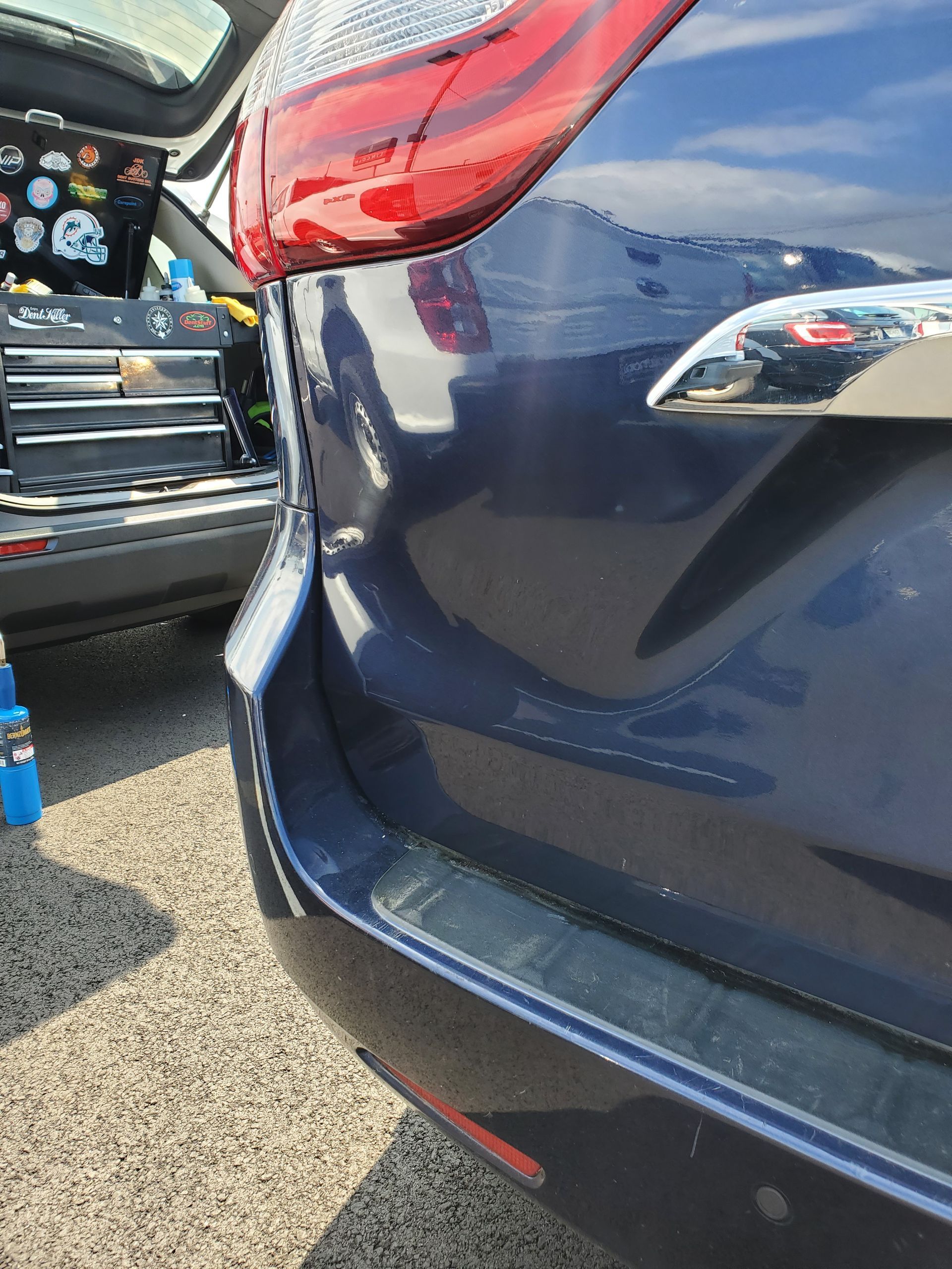 Close-up of a dark blue SUV’s rear bumper and hatch beside another car in a parking lot.