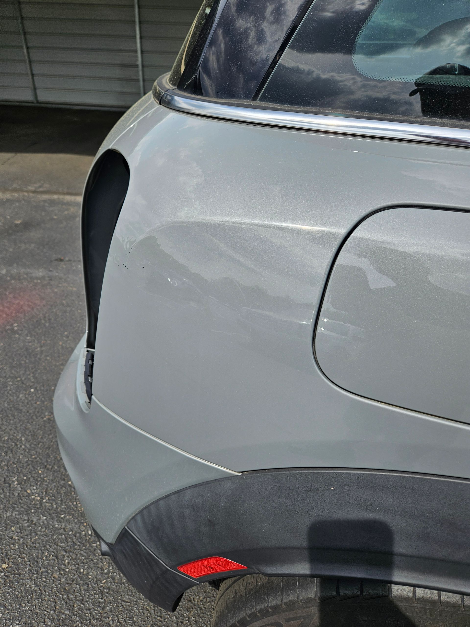 Close-up of a gray car’s rear quarter panel with a damaged or missing taillight area.