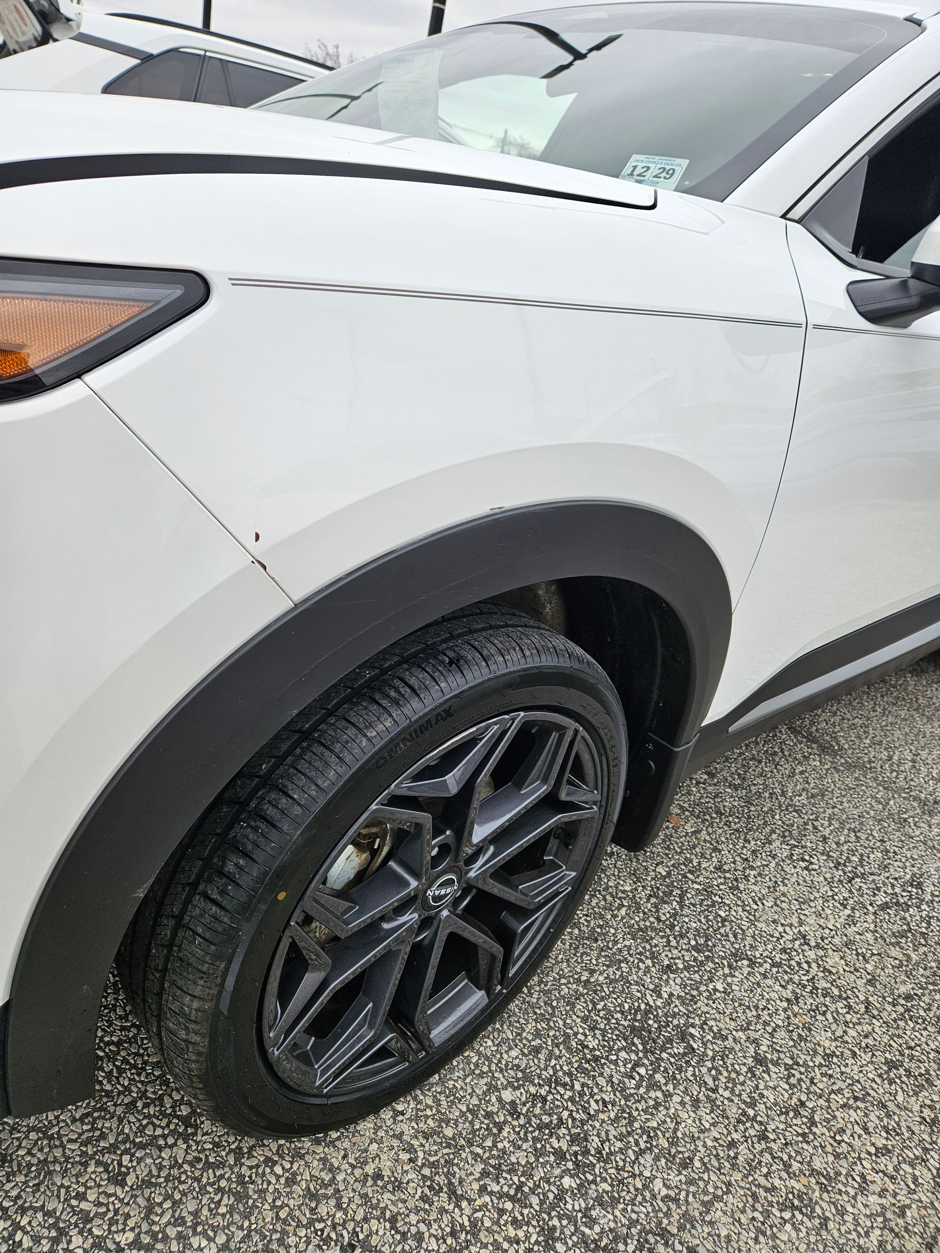 Close-up of a white SUV’s front side and wheel on wet pavement