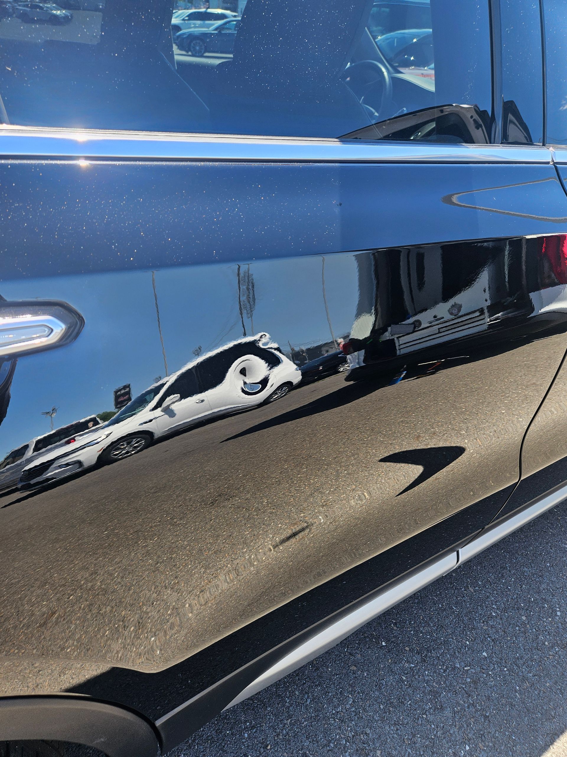 Close-up of a blue car’s side door with a long black-and-white reflection on the glossy paint.