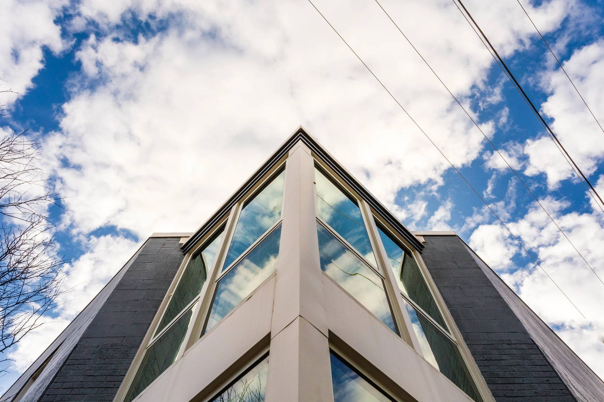 Modern building facade viewed from below against a blue sky with clouds