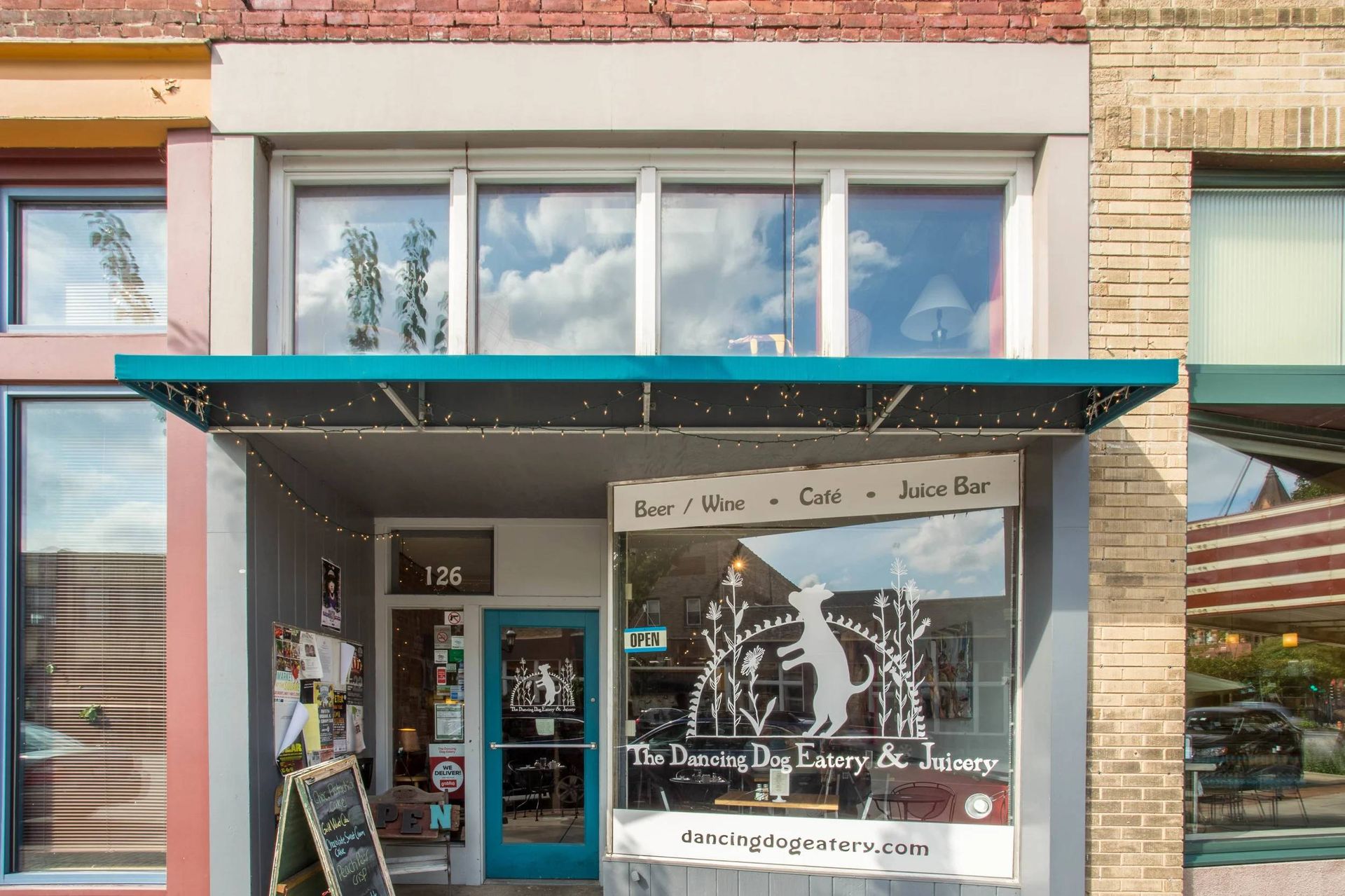Storefront with teal awning, brick facade, and large bakery window display on a city street