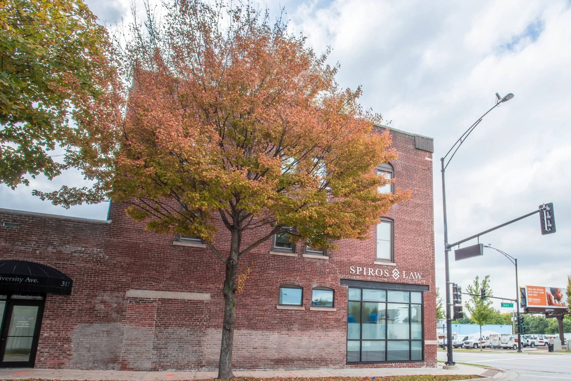 Brick building with glass entrance and autumn tree on a city street corner