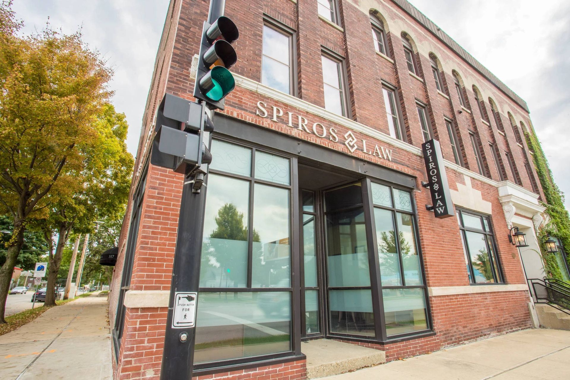 Corner brick storefront with large windows, green awning, and traffic light at a city intersection