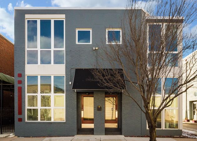 Modern gray two-story house with large windows and a bare tree in front
