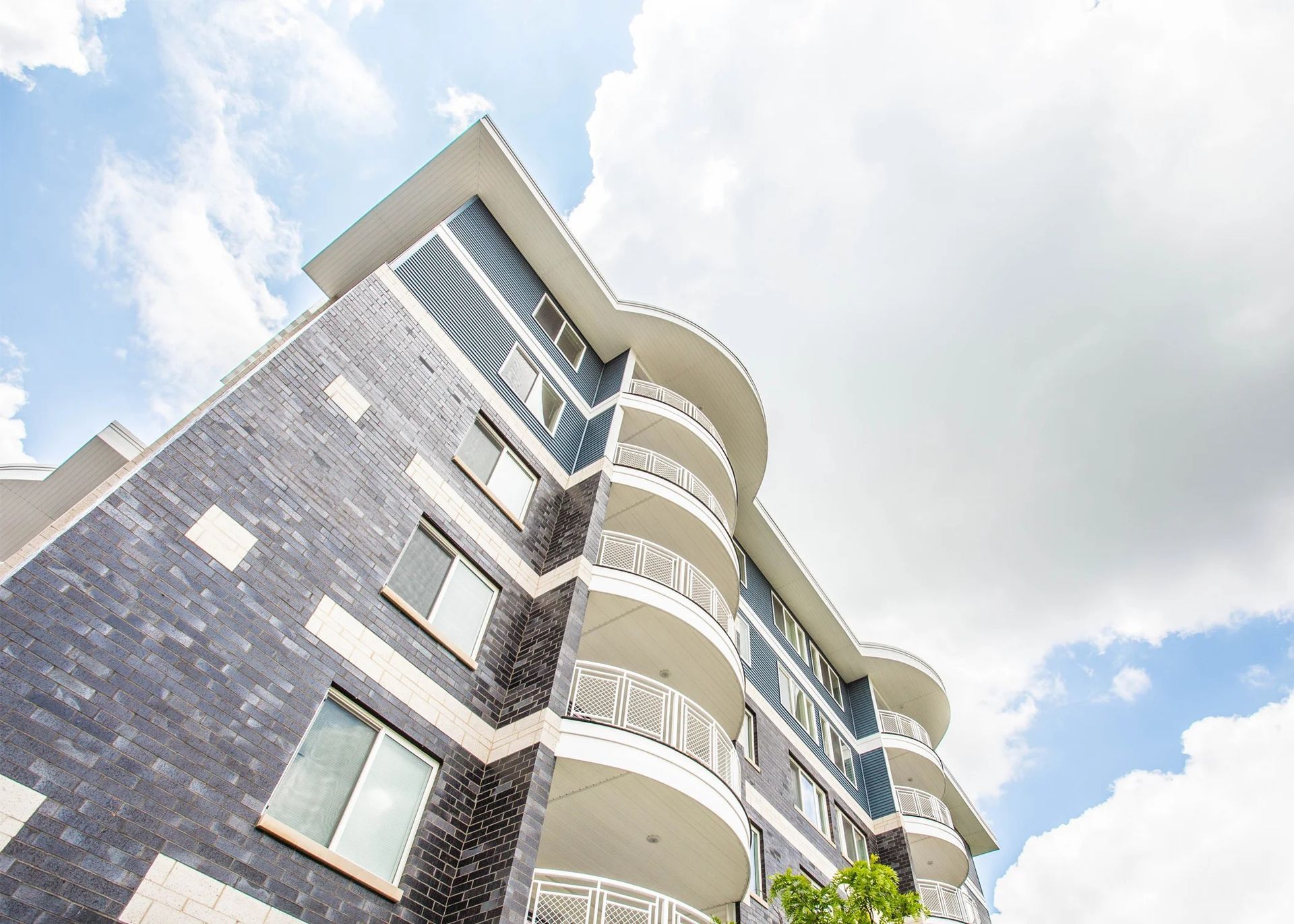 Modern apartment building with curved balconies against a bright cloudy sky