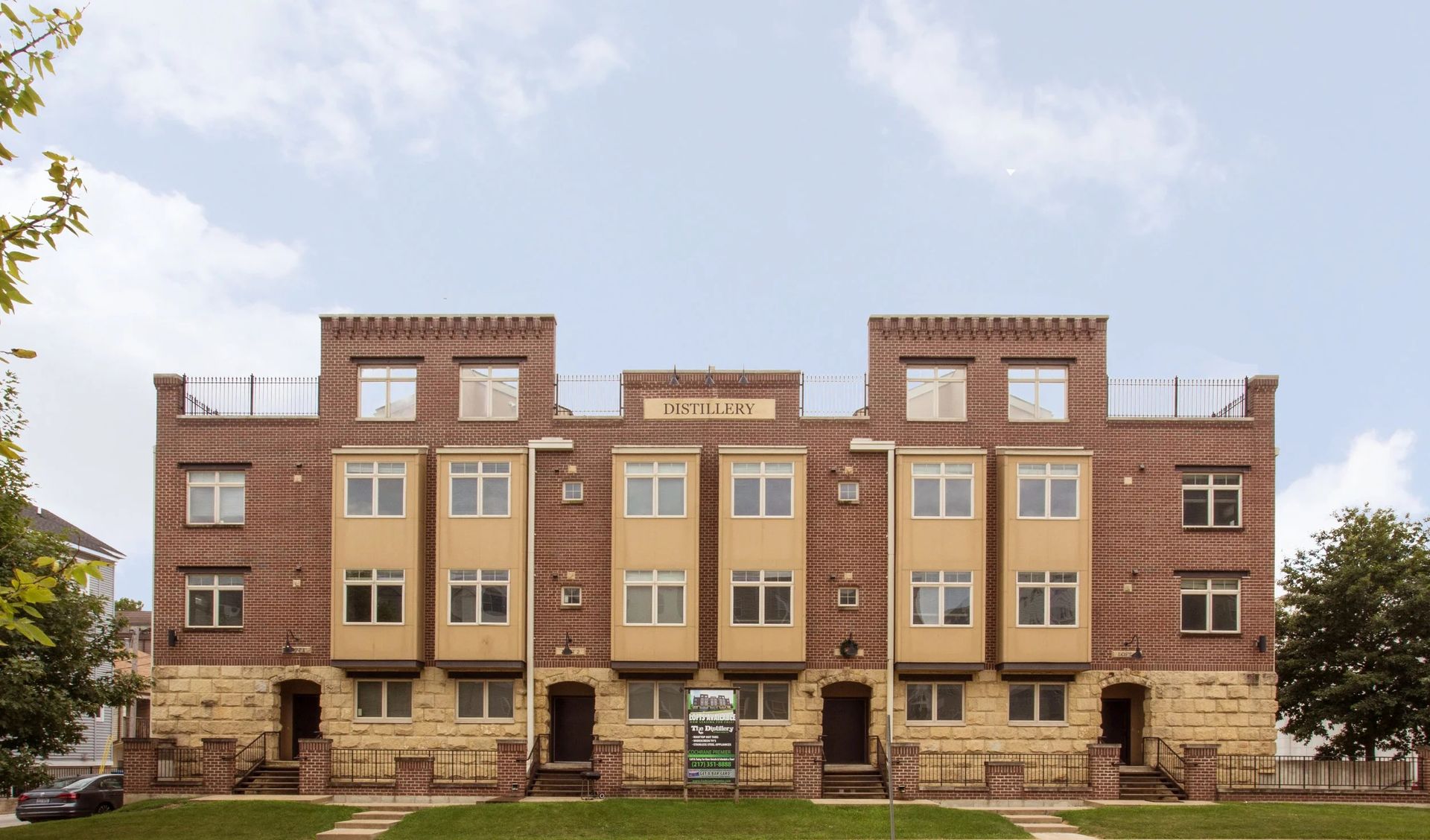 Brick apartment building with beige bay windows and small front steps under a blue sky