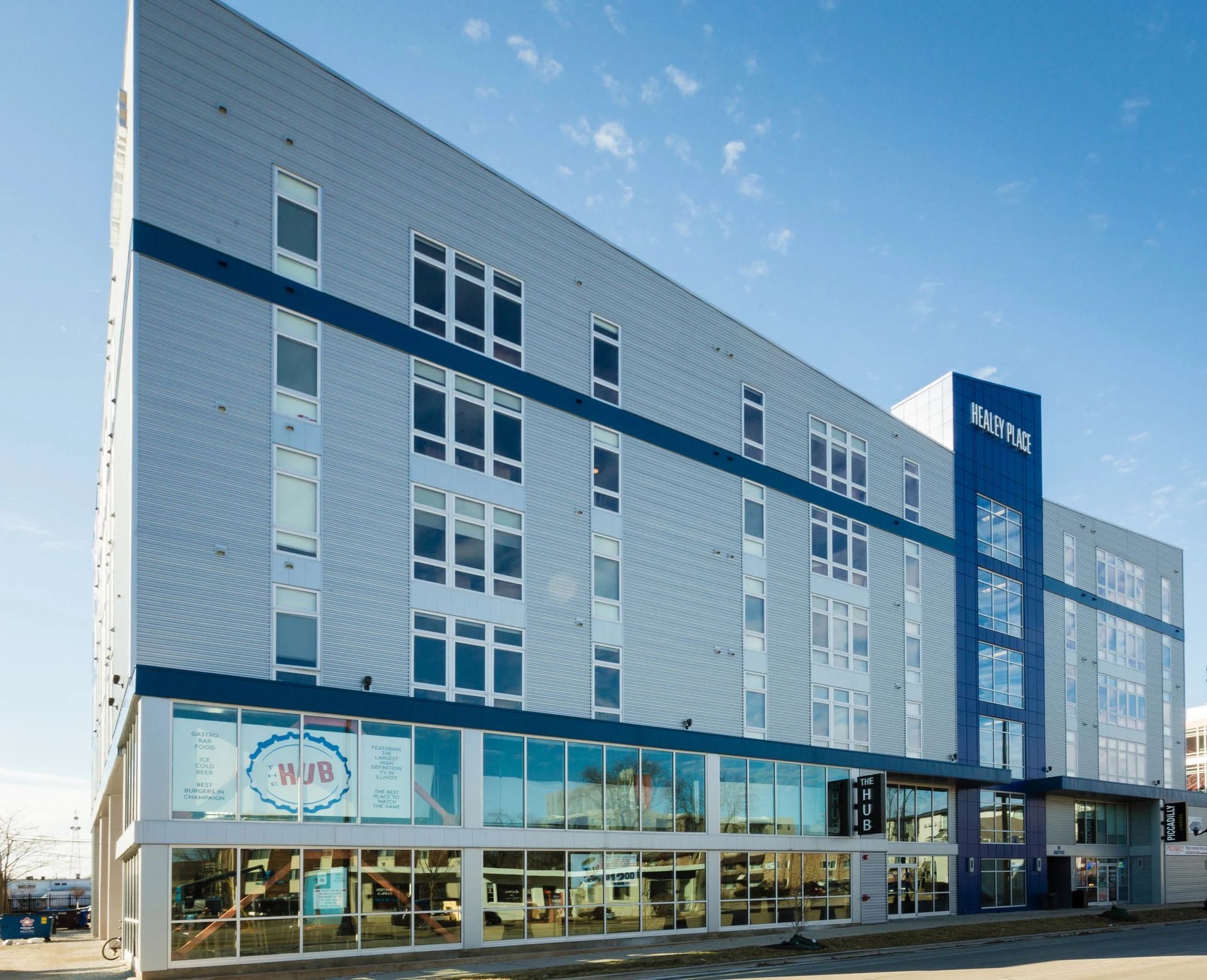 Modern multi-story building with a glass storefront and blue accents under a clear sky
