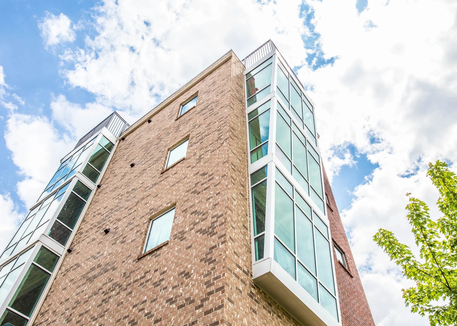 Modern brick apartment building with glass balconies against a bright sky