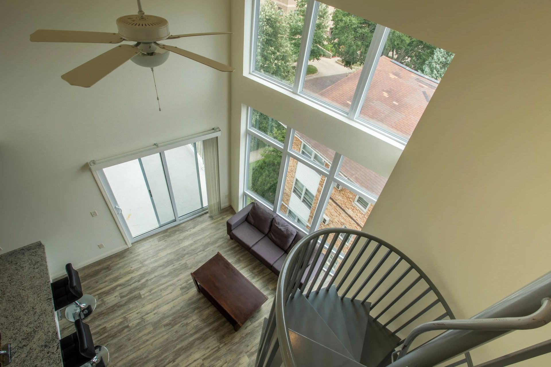 Loft living room with high windows, ceiling fan, staircase, sofa, and coffee table