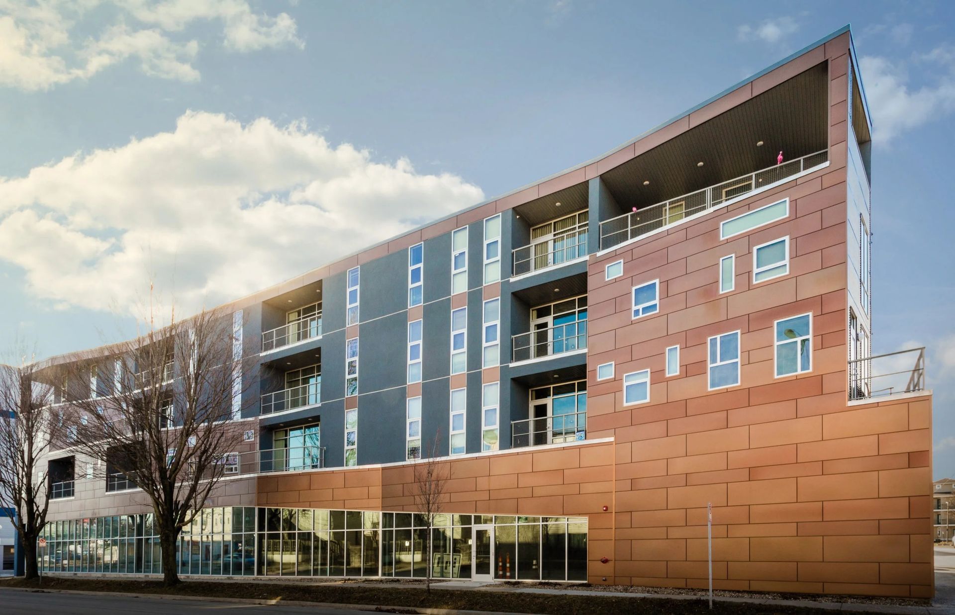 Modern multi-story brick and glass apartment building with balconies and a curved roofline