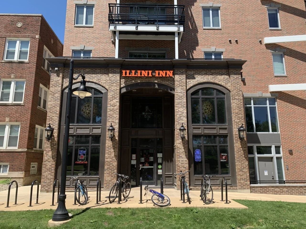 Entrance to an Illinois building with brick facade, arched doorway, bikes, and a streetlamp in front