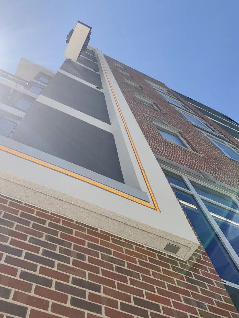 Low-angle view of a brick-and-glass building against a clear blue sky
