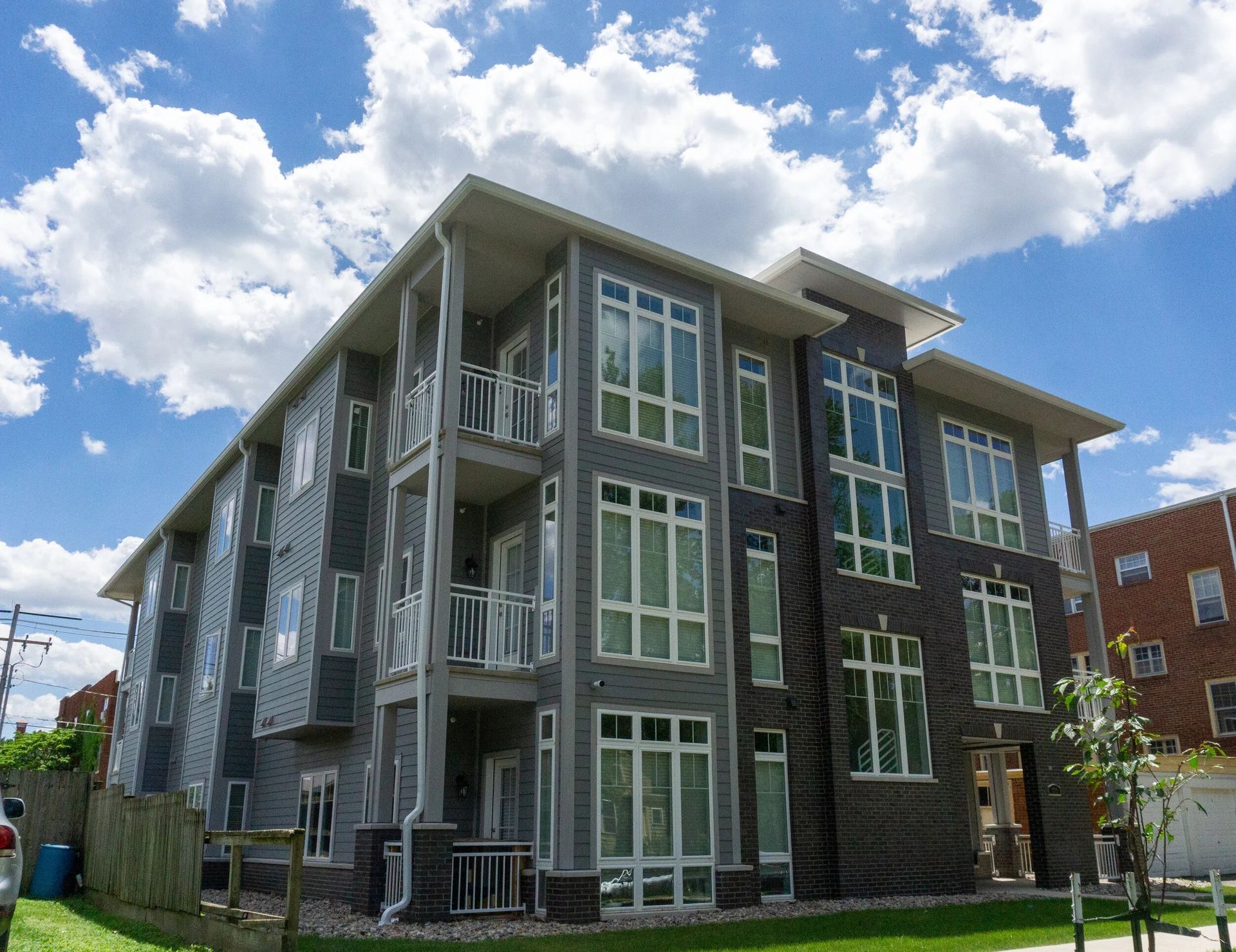Modern gray apartment building with large windows under a blue sky with clouds