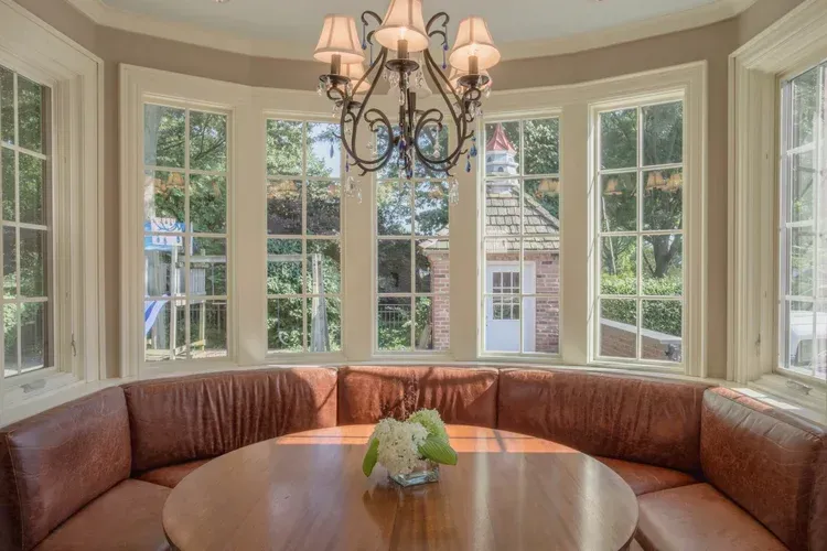 Curved bay window seating area with a round wooden table and chandelier in a bright room
