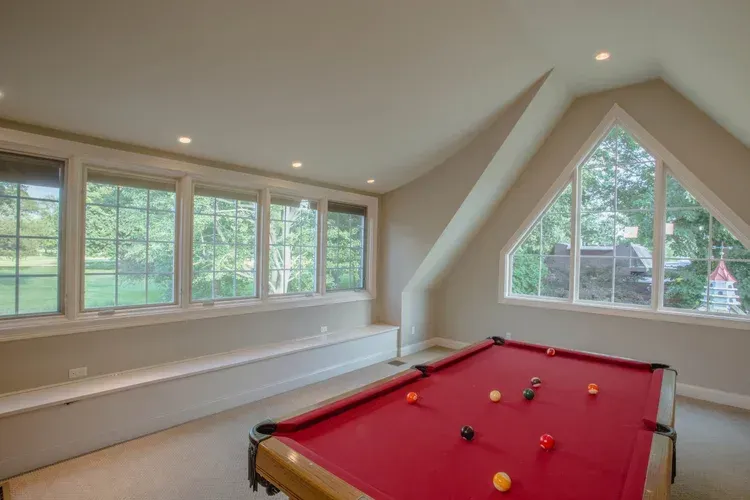 Bright attic game room with large windows and a red pool table
