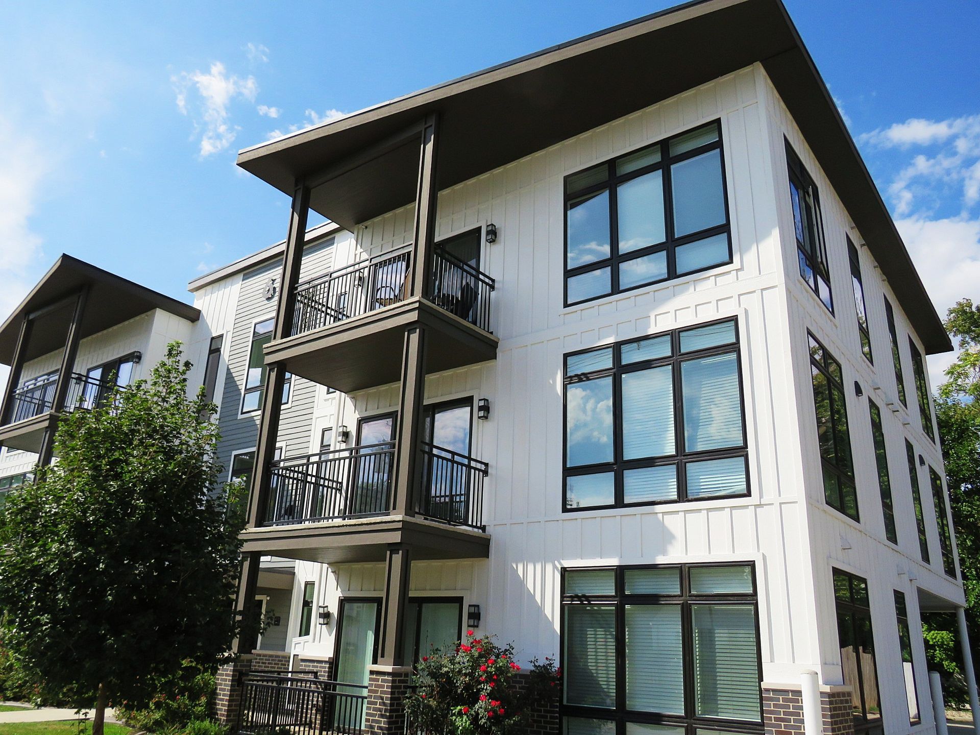 Modern apartment building with balconies, large windows, and white walls under a blue sky
