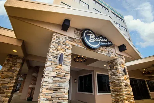 Exterior entrance of a building with stone columns and a circular sign under a slanted roof
