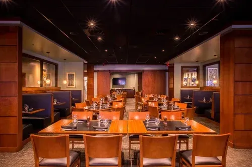 Empty restaurant dining room with orange tables, wooden chairs, and warm ambient lighting
