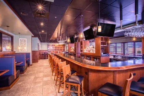 Empty modern bar with blue booths, wooden stools, and warm ambient lighting